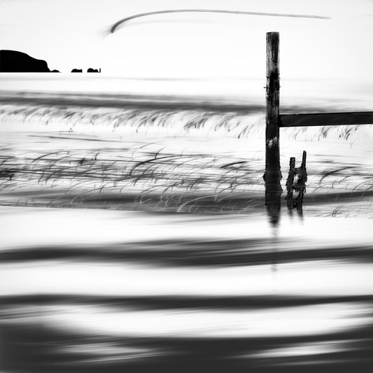 Storm Marker — weathered wooden post in swirling motion-blurred water with a sweeping arc across the sky, black and white fine art photography by Roy Fraser