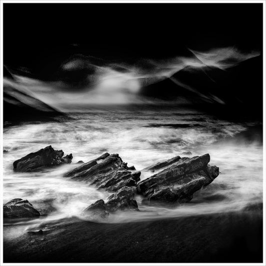 Night Surge — jagged dark rocks engulfed by swirling white water under a dramatically dark painterly sky, black and white fine art photography by Roy Fraser