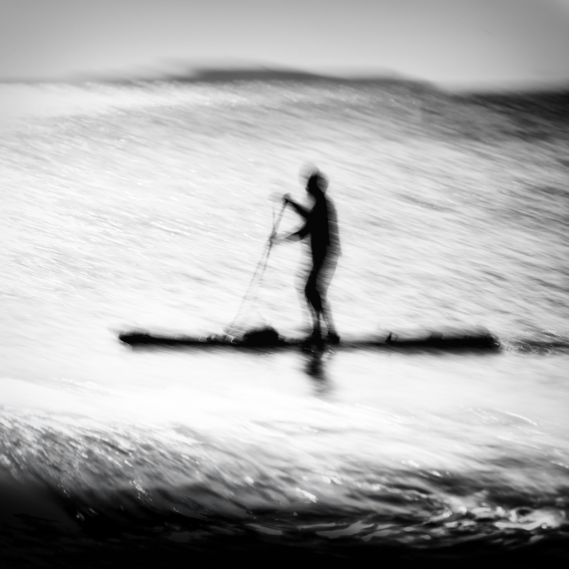 Hikari no Umi — lone paddleboarder silhouette on a glittering silver sea, black and white fine art photography